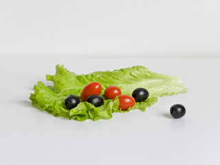 Lettuce and tomatoes with olives on white background
