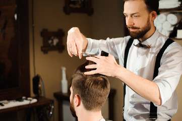 Fototapeta premium Master cuts hair and beard of men in the barbershop