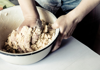 Women's hands knead the dough, make pie.
