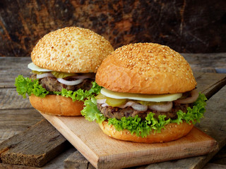 veggie burgers with a chop of black beans, lettuce, pickled onions, cucumber on a wooden background.