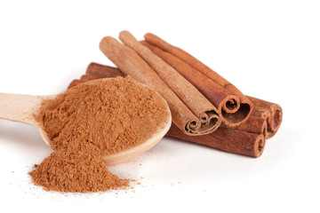 three cinnamon sticks and powder with spoon isolated on white background