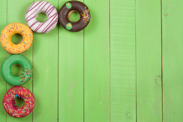 glazed donuts on a green wooden background with copy space for your text. Top view