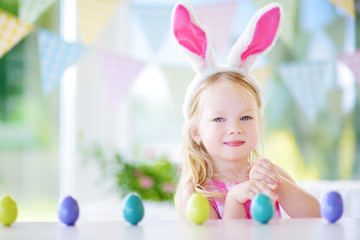 Obraz na płótnie Canvas Cute little girl wearing bunny ears playing egg hunt on Easter