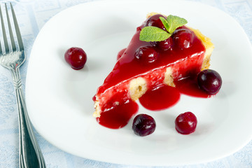 Homemade cherry cheesecake in white plate on light cloth napkin