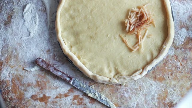 A woman is preparing an apple pie in a home kitchen
