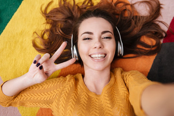 Smiling pretty girl in headphones showing peace gesture