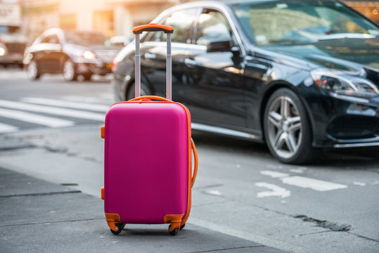 Luggage bag on the city street ready to pick by airport transfer taxy car.