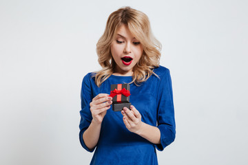 Surprised young woman holding little gift box