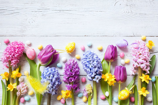 Easter wooden background with flowers, eggs and candy