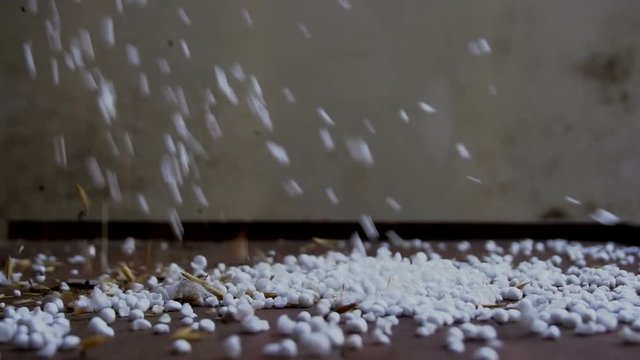 Slow motion abstract polystyrene balls with debris falling on the floor