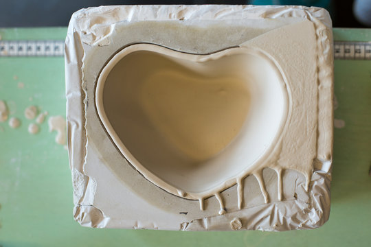 Top view of a mold with shape of a heart bowl  filled with ceramic liquid. Flat lay.