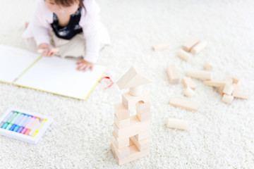 Baby girl drawing next to wooden building blocks