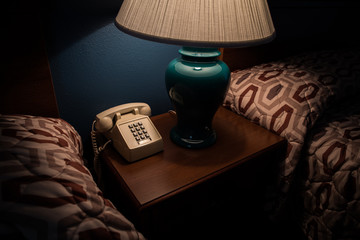 Old phone and lamp on a bedside table in a hotel room - obrazy, fototapety, plakaty