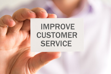 Businessman holding a card with IMPROVE CUSTOMER SERVICE message