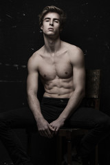 Young Handsome man with great fit body posing at the chair 
