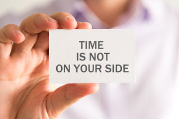Businessman holding a card with TIME IS NOT ON YOUR SIDE message