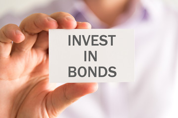 Businessman holding a card with INVEST IN BONDS message