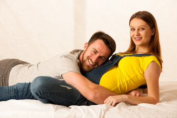 happy couple - man listening to pregnant woman belly