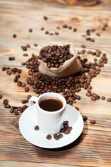 cup of coffee with grains on the wooden background