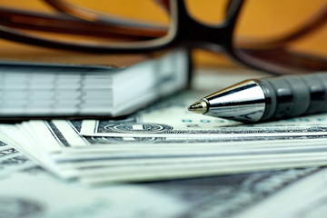 Ball pen and small notebook on US dollar banknote
