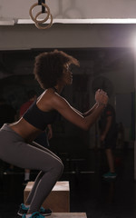 black female athlete is performing box jumps at gym