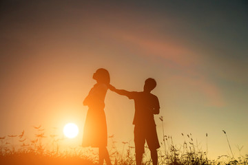 a silhouette of a man and woman holding hands with each other, walking together