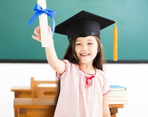 Portrait of  cute schoolgirl with graduation hat in classroom