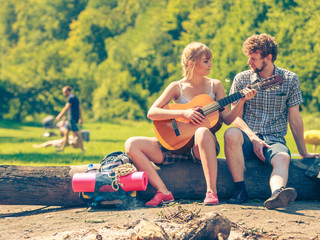 Young couple camping playing guitar outdoor