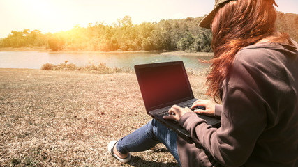 Woman working in a natural park using a notebook.