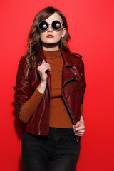 fashion model in sunglasses, beautiful young woman. leather jacket, studio shot