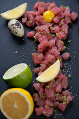 Close-up of tuna tartar with quail egg yolk, lemon and lime, selective focus