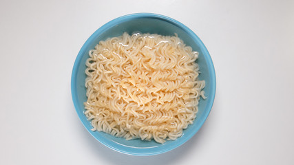 TOP VIEW: Quick noodles in blue bowl in hot water