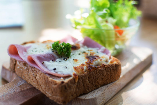 Delicious crusty baguette sandwich with ham cheese and salad on a wooden table