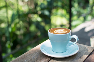 blue cup of hot coffee on natural green background