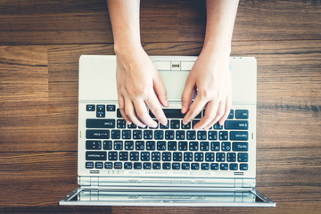 Woman hand working on laptop on wooden table