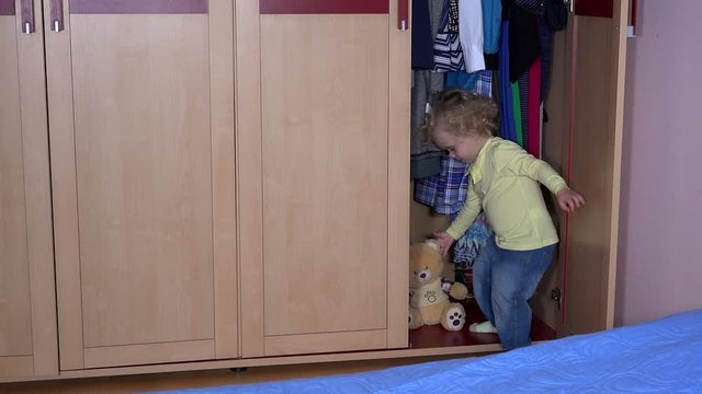 Adorable child kid hide best friend teddy bear into closet and close door