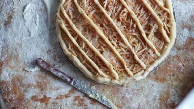 A woman is preparing an apple pie in a home kitchen