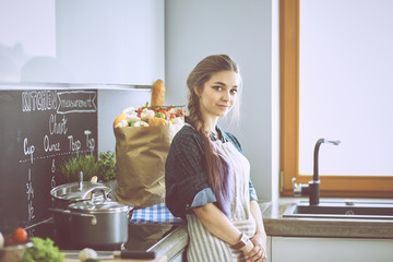 Obraz na płótnie Canvas Young woman standing by the stove in the kitchen