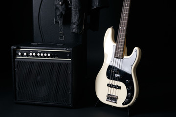 Black and white electric bass guitar with amplifier,hard case and Leather biker jacket.Copy spase.