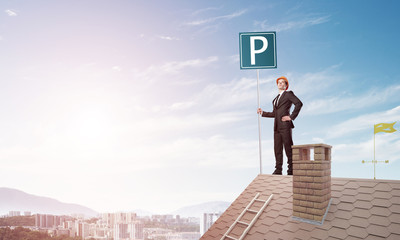 Young businessman with parking sign standing on brick roof. Mixed media