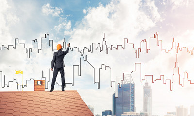 Man architect draw silhouette of modern city on blue sky. Mixed 