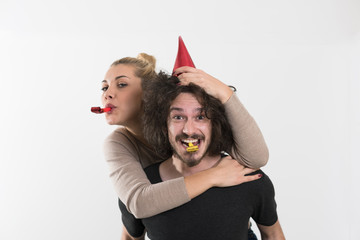 couple in party hats blowing in whistle