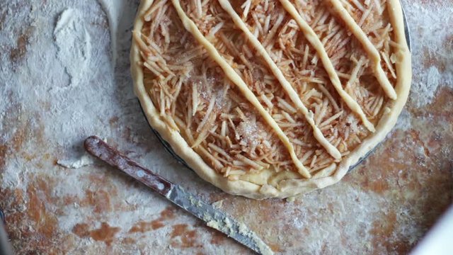 A woman is preparing an apple pie in a home kitchen
