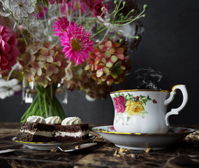 Closeup of cup of tea with cake and flowers bouquet on the wood table close up photo