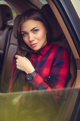 Obraz na płótnie Canvas Brunette female in a red fleece shirt sits in a car.