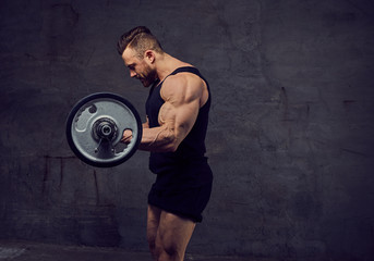 A huge bearded bodybuilder working out with barbells.