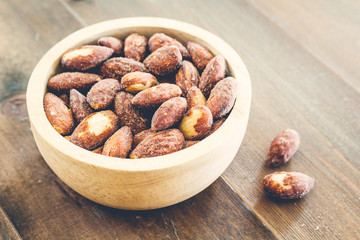 Almonds in bowl on  wooden background