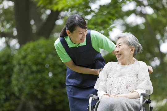 Healthcare worker pushing senior woman in wheelchair, Tokyo Prefecture, Honshu, Japan