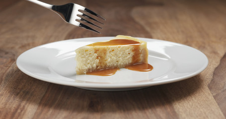 eating caramel cheesecake with fork on wood table, 4k photo