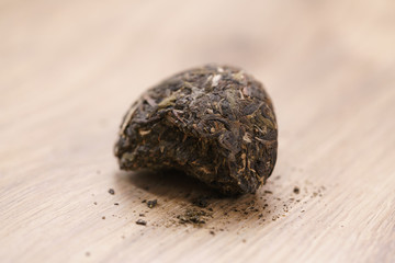 part of raw green puerh tea on wood table, shallow focus